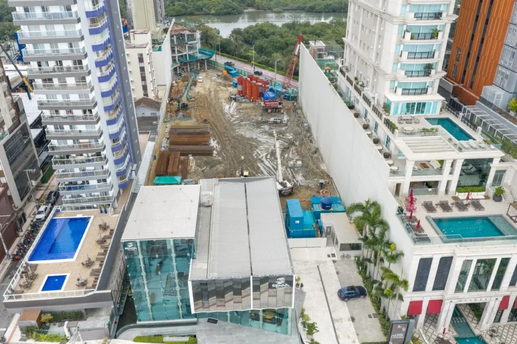 Obra do Senna Tower em setembro de 2026, com o showroom em primeiro plano e o canteiro ao fundo, em Balneário Camboriú